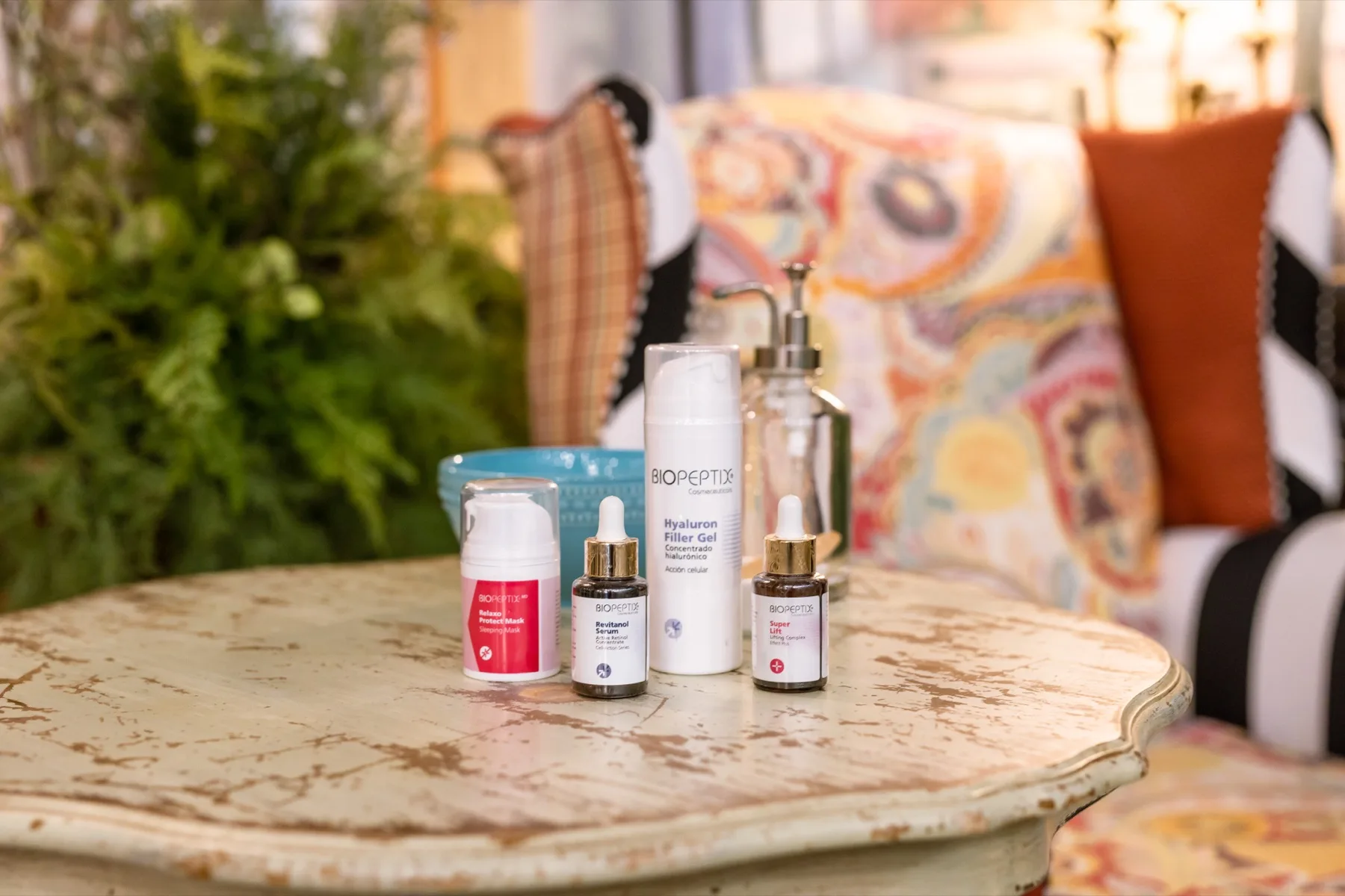 Peptide serums and moisturizers from our retail collection on an antique table in the sunlit ESSpa lounge