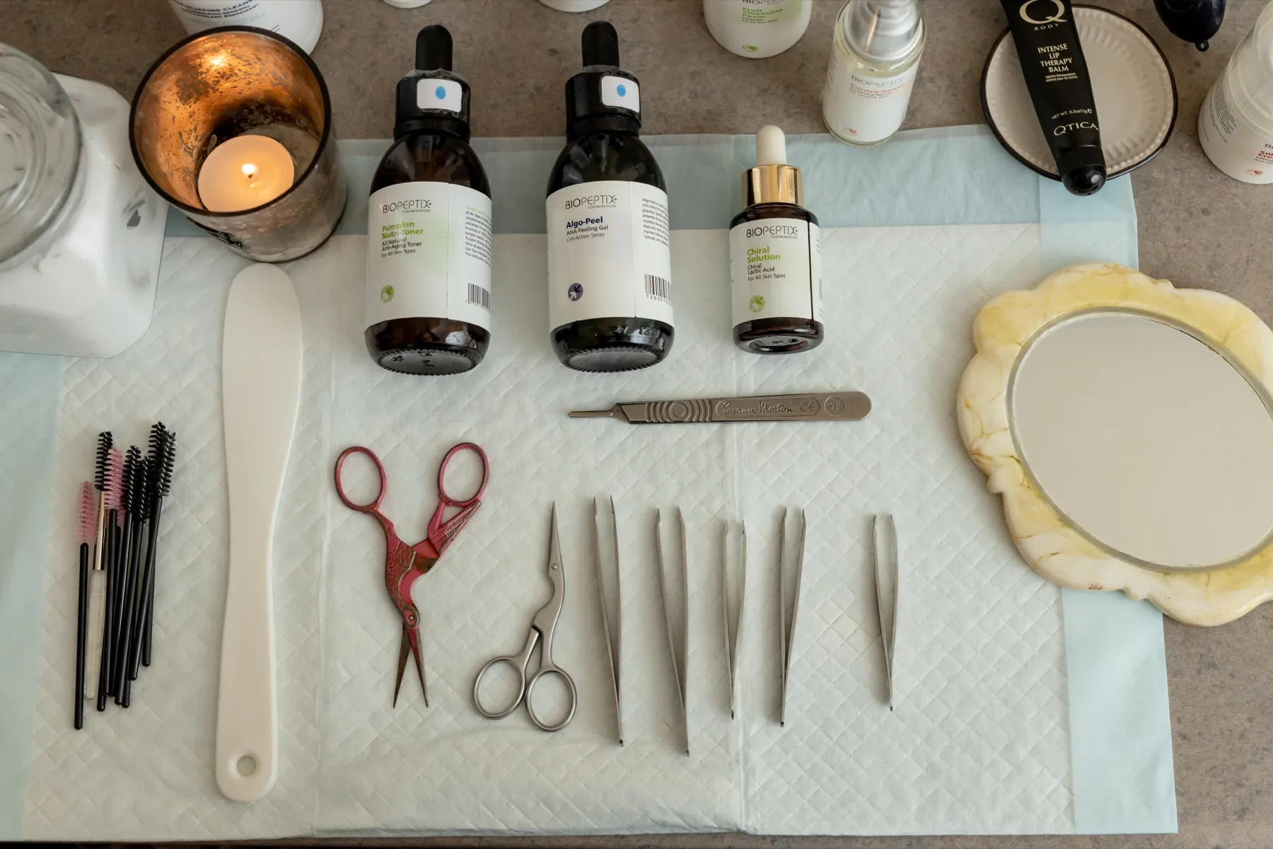 Amber dropper serums arranged with sterilized precision tools and a lit candle on a fresh treatment tray at ESSpa Kozmetika