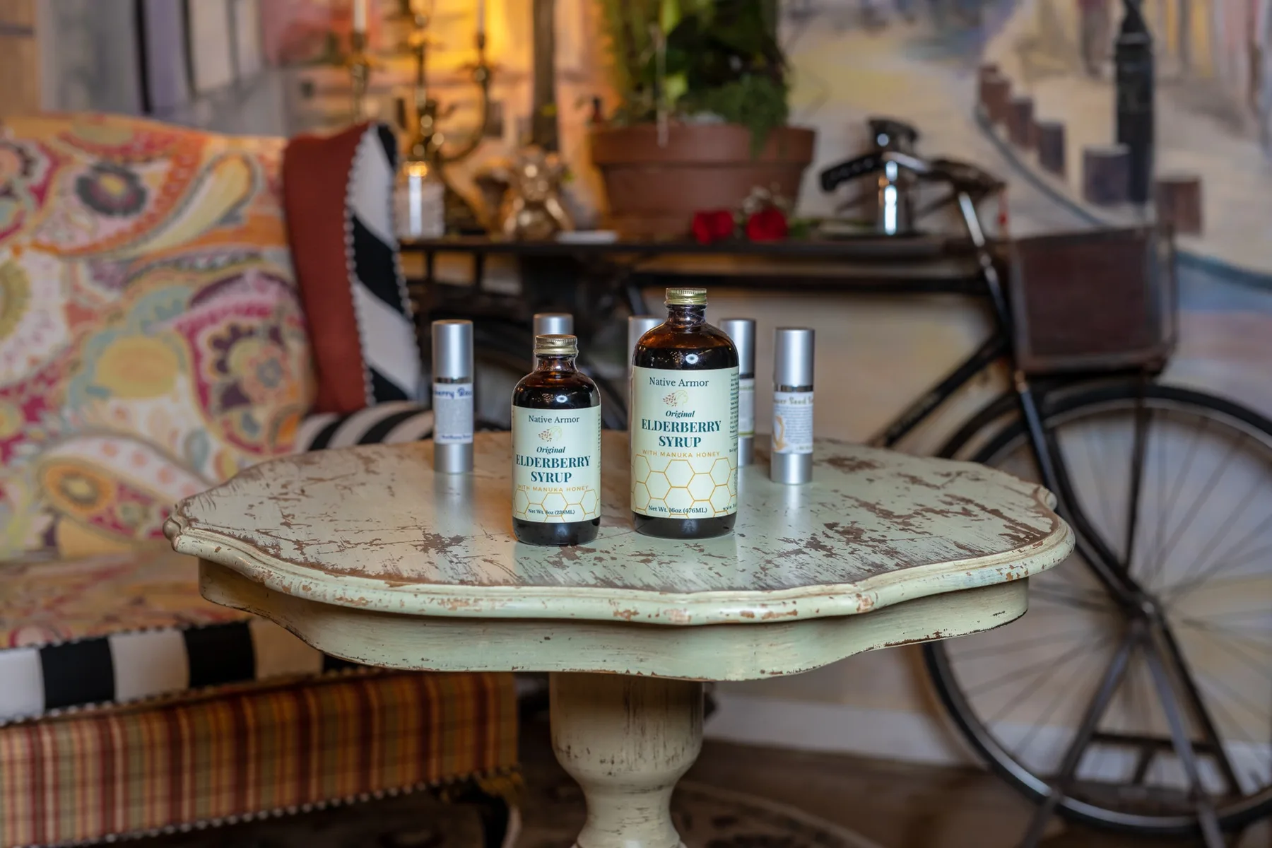 Amber apothecary bottles of botanical elderberry syrup and slim serum tubes arranged on an antique table in our Aspinwall spa