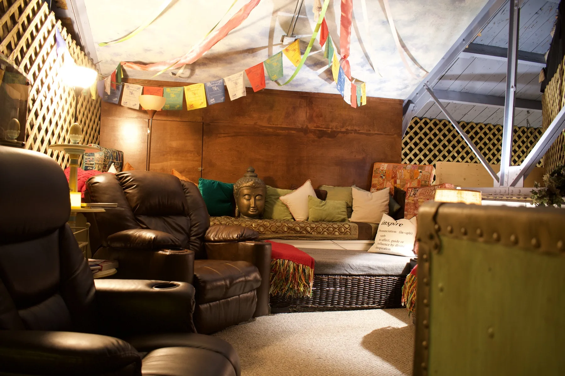 Our warmly lit relaxation lounge at ESSpa, with cushioned leather recliners, a serene Buddha and prayer flags overhead