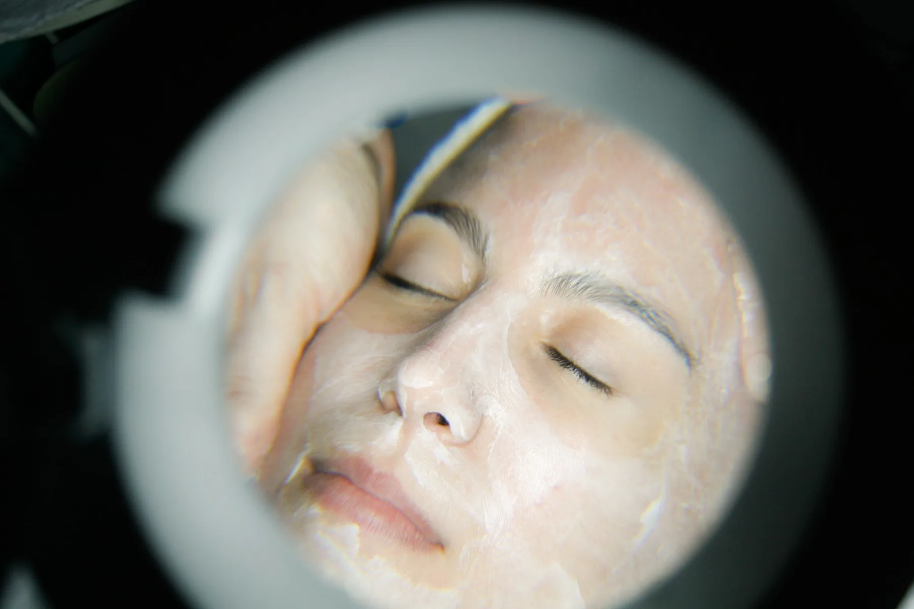 A close-up of a guest's face during a facial at our Aspinwall spa, skin glowing and brows softly defined under the esthetician's magnifying lamp