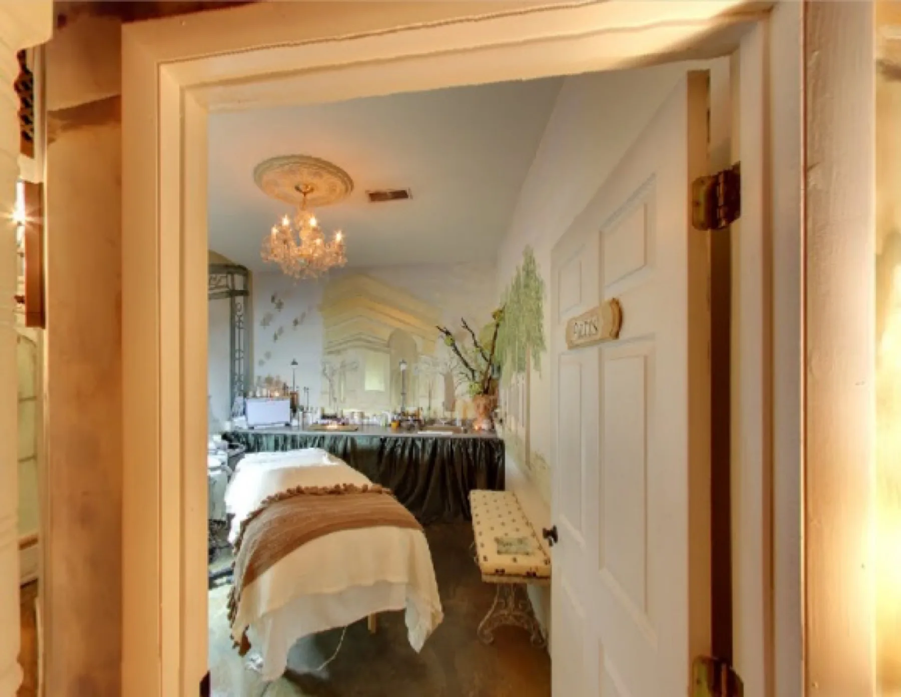 A warm, chandelier-lit treatment room at our Aspinwall spa, glimpsed through the doorway